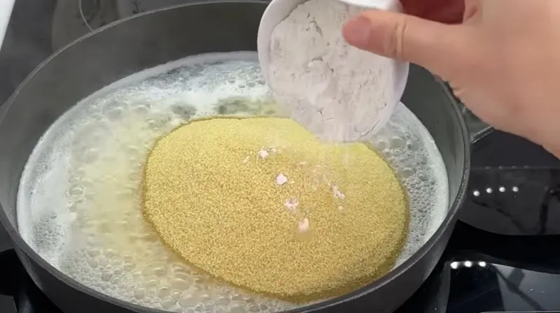 ریختن شکر دانه‌ای به آرد سمولینا تفت داده شده