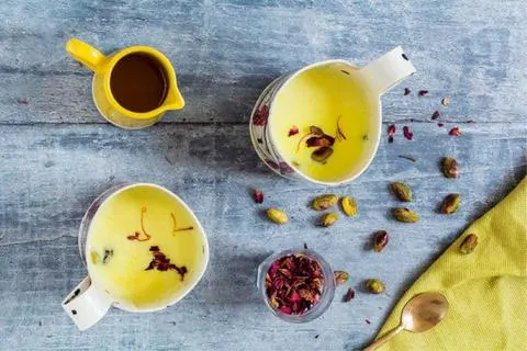 افزودن شهد زعفرانی به مخلوط آرد و روغن در حال هم زدن