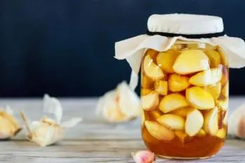 شیشه ترشی سیر با زردچوبه با رنگ طلایی و حبه‌های سیر سالم