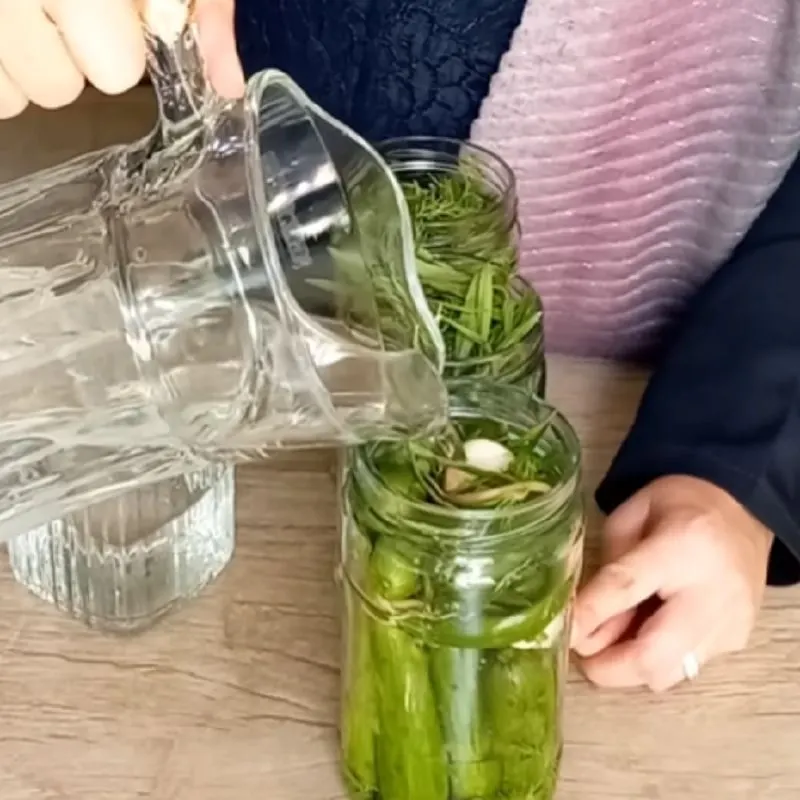 قابلمه حاوی شیشه‌های خیارشور در حال حرارت دادن