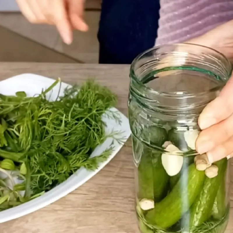 قرار دادن سبزی معطر روی خیارها در شیشه