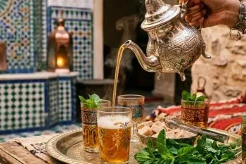 فنجان چای مراکشی با برگ‌های نعناع تازه و کف روی سطح چای