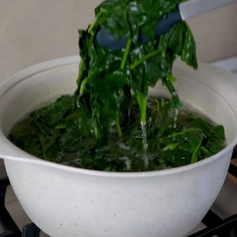 خارج کردن اسفناج از آب جوش پس از بلانچ کردن