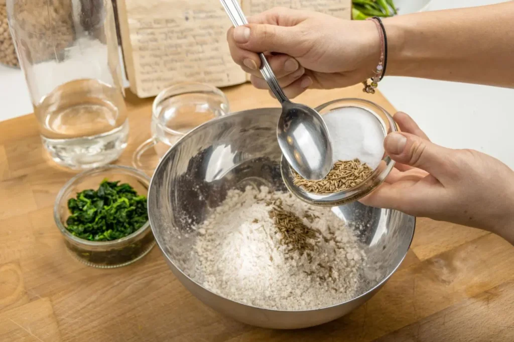 افزودن شیر و روغن به مواد خشک برای تهیه خمیر کلوچه