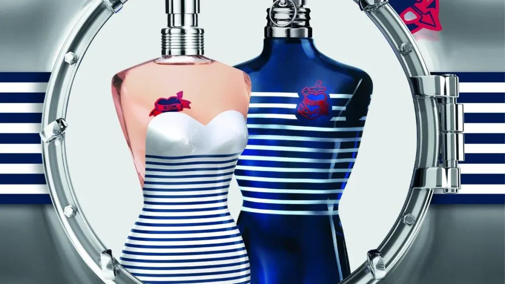 چند شیشه عطر زنانه در کنار گل‌های رز و یاس